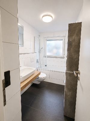 Salle de bain rénovée avec baignoire et douche